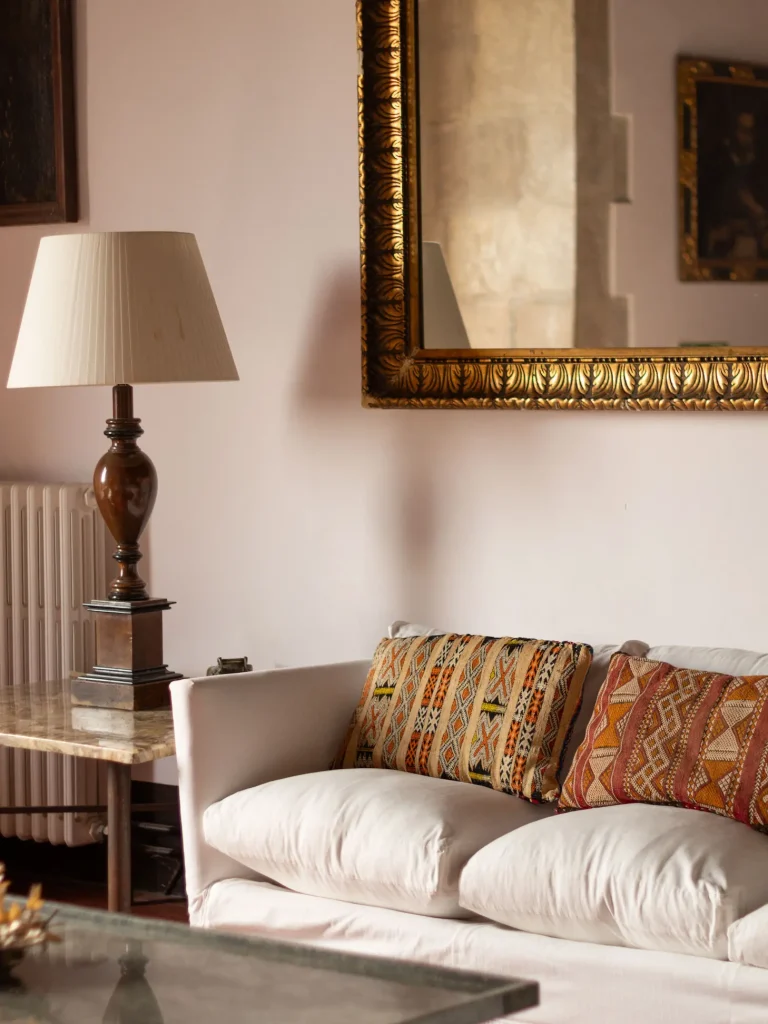 Salón con sofá blanco, cojines decorativos y lámpara clásica