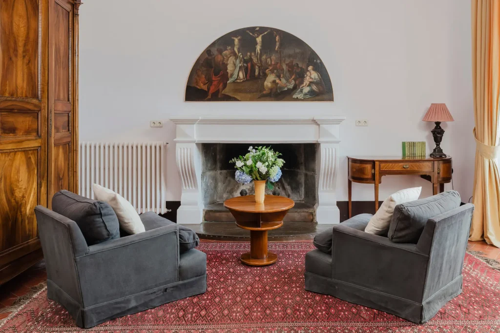 Sala de estar elegante con chimenea y sillones grises en el Castell de Sant Mori