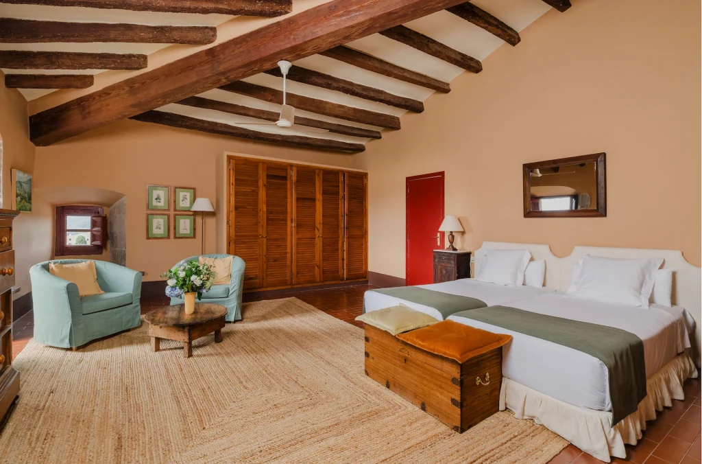 Habitación amplia y luminosa con vigas de madera en el Castell de Sant Mori