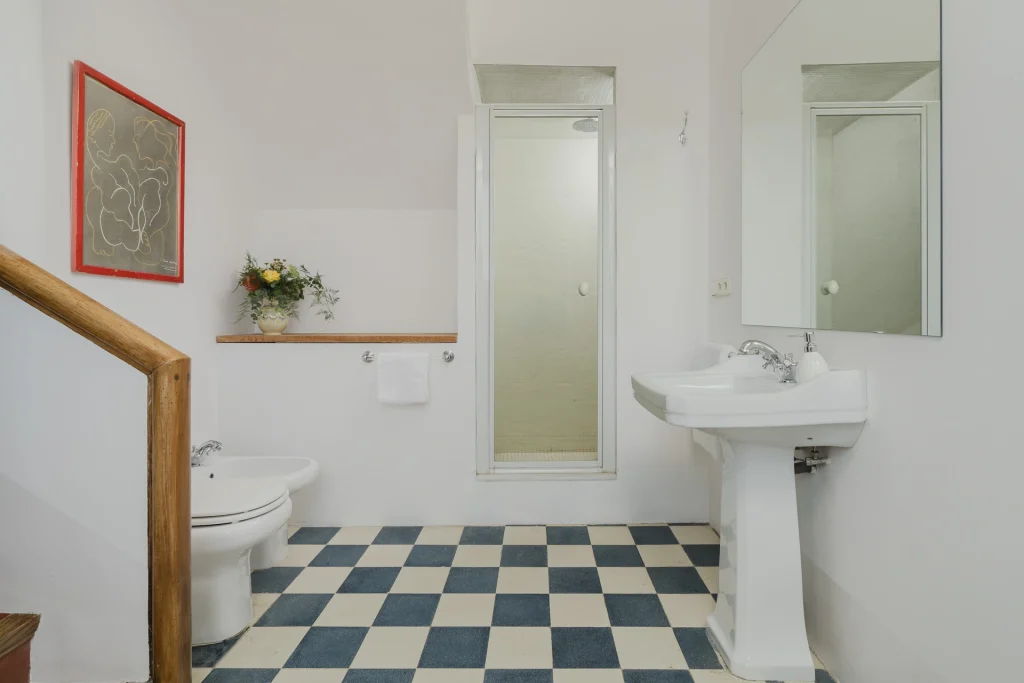 Baño con entrada amplia y suelo de damero