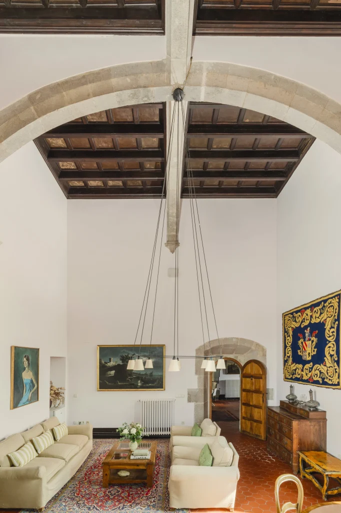 Sala noble con techos de madera y araña central.