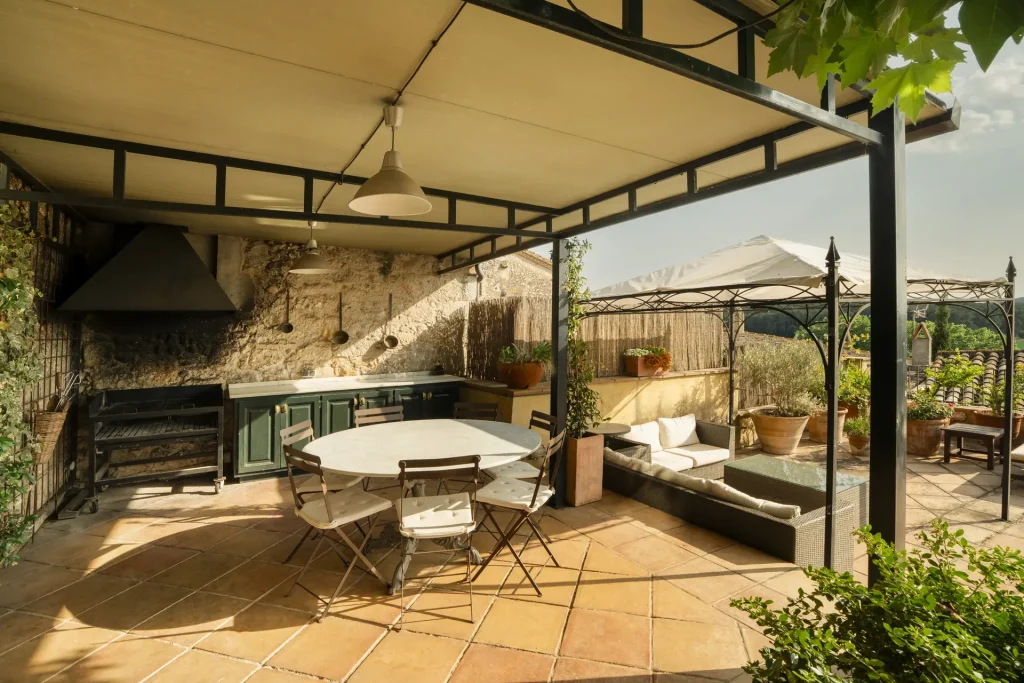 Àrea exterior amb barbacoa i menjador sota pèrgola