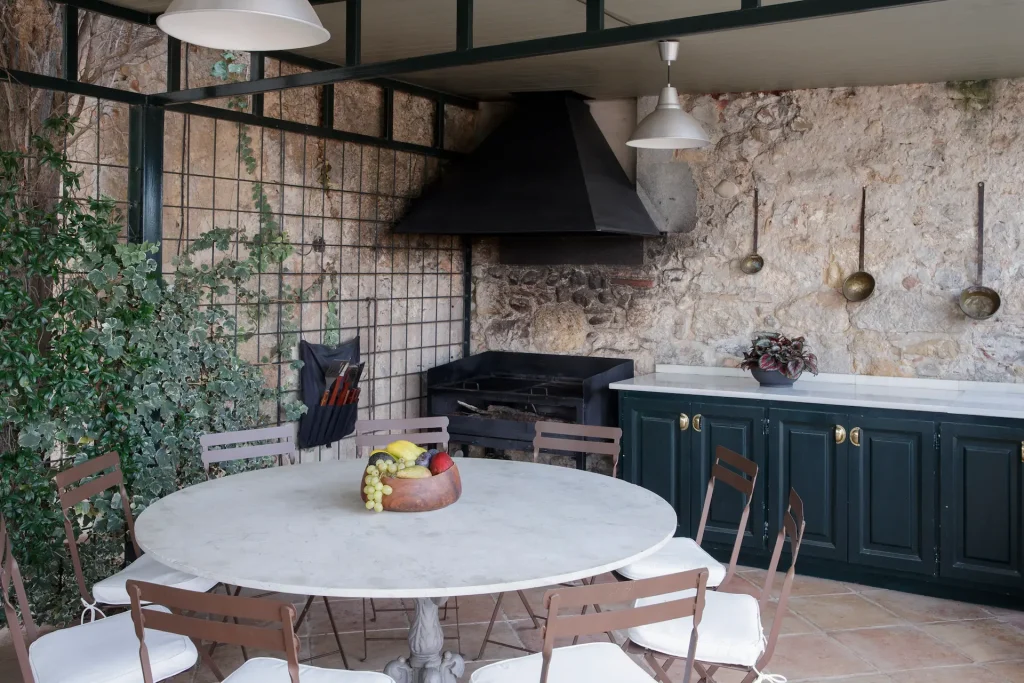 Cocina exterior rústica con mesa redonda en el Castell de Sant Mori