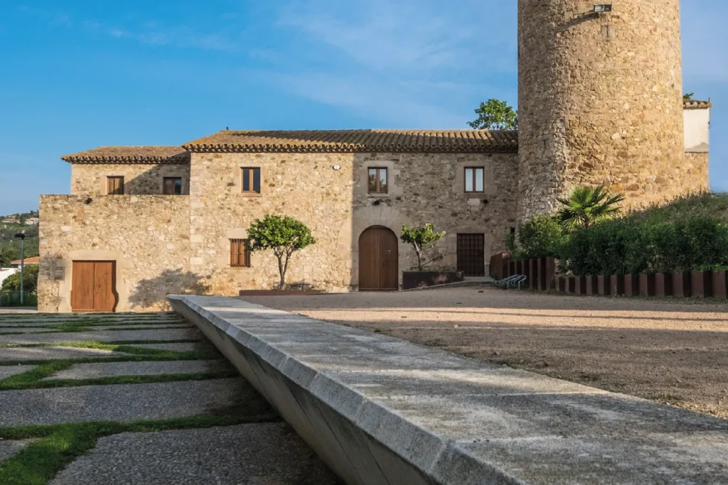 Masía de piedra restaurada con torre y patio empedrado